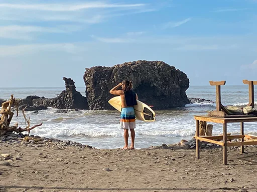 El Tunco Surfer Surfer holding a board and looking out at the ocean.